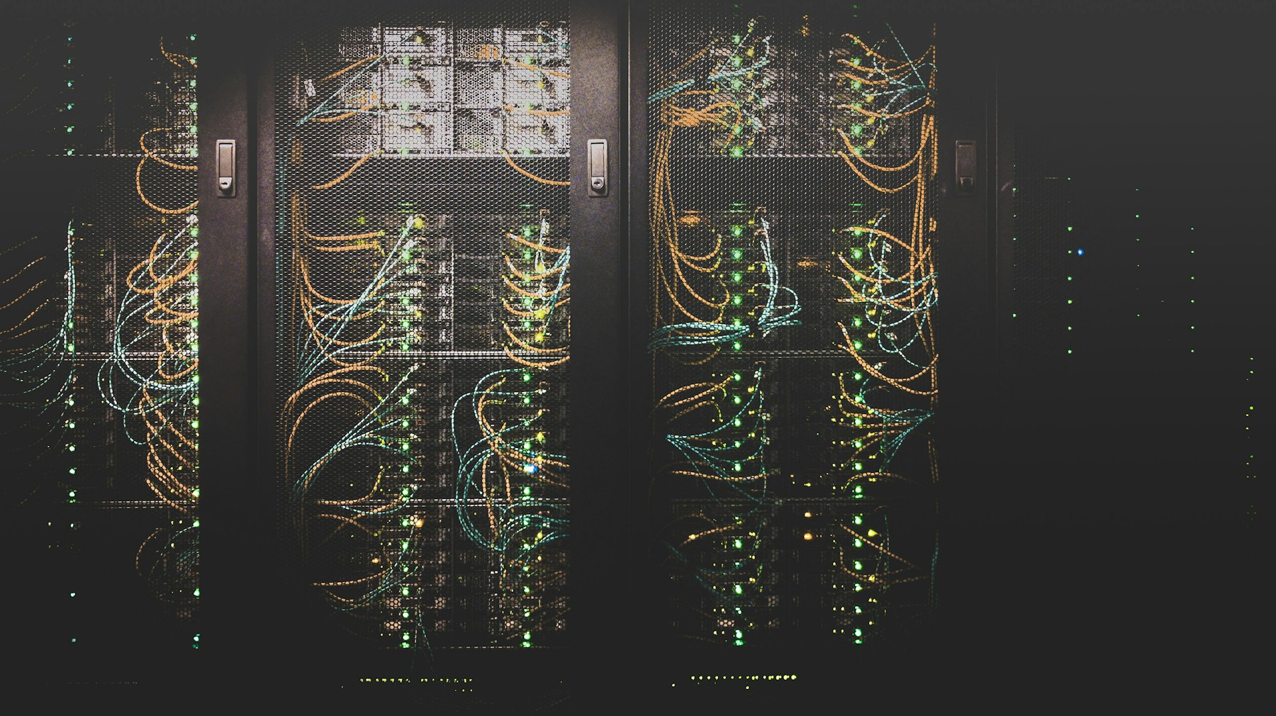 Server racks with patched fibre cabling — atmospheric, low-key lit