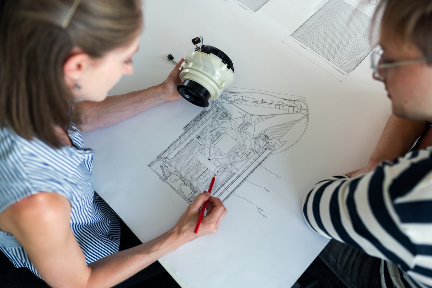 Two engineers reviewing a technical drawing alongside a physical part